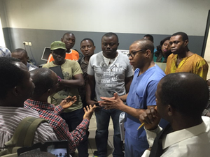 DR. FAROUK DAKO (CENTER IN BLUE) SPEAKING WITH A GROUP OF BIOMEDICAL ENGINEERS AT LAGOS UNIVERSITY TEACHING HOSPITAL IN NIGERIA ABOUT WAYS TO ADVANCE MAINTENANCE AND REPAIR OF MEDICAL DEVICES LOCALLY.